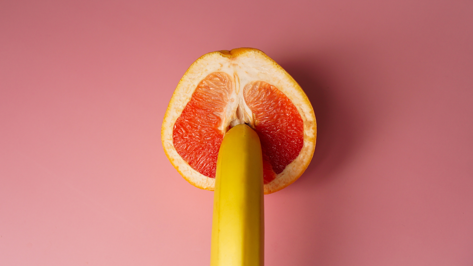 Une banane est posée sur un pamplemousse, qui est en forme ressemblant à de génital féminin.